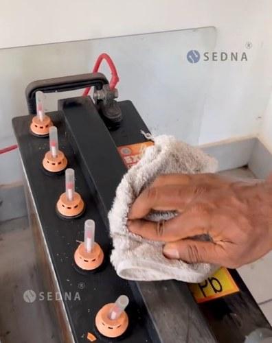 A SEDNA technician cleaning a battery during a service visit